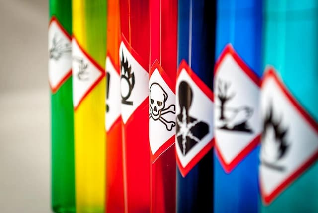 Color-coded chemical containers with GHS hazard symbols for toxicity, flammability, and environmental danger