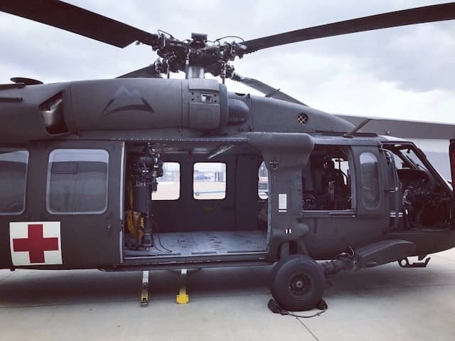 MEDEVAC Black Hawk on tarmac with doors open and red-cross marking—symbolizing emergency evacuation after a banded sea krait bite on Survivor